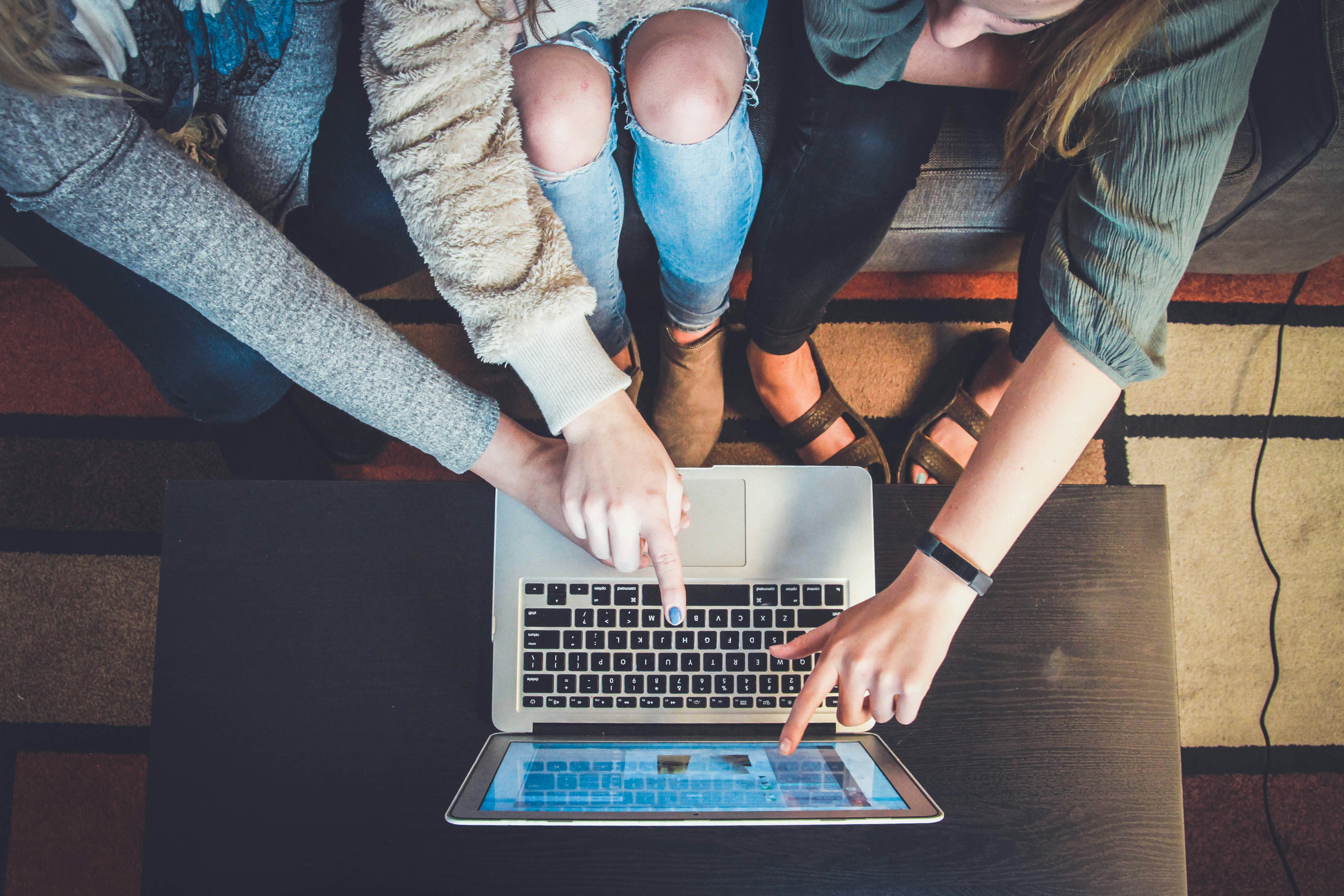 A group of people collaborating by typing on a laptop