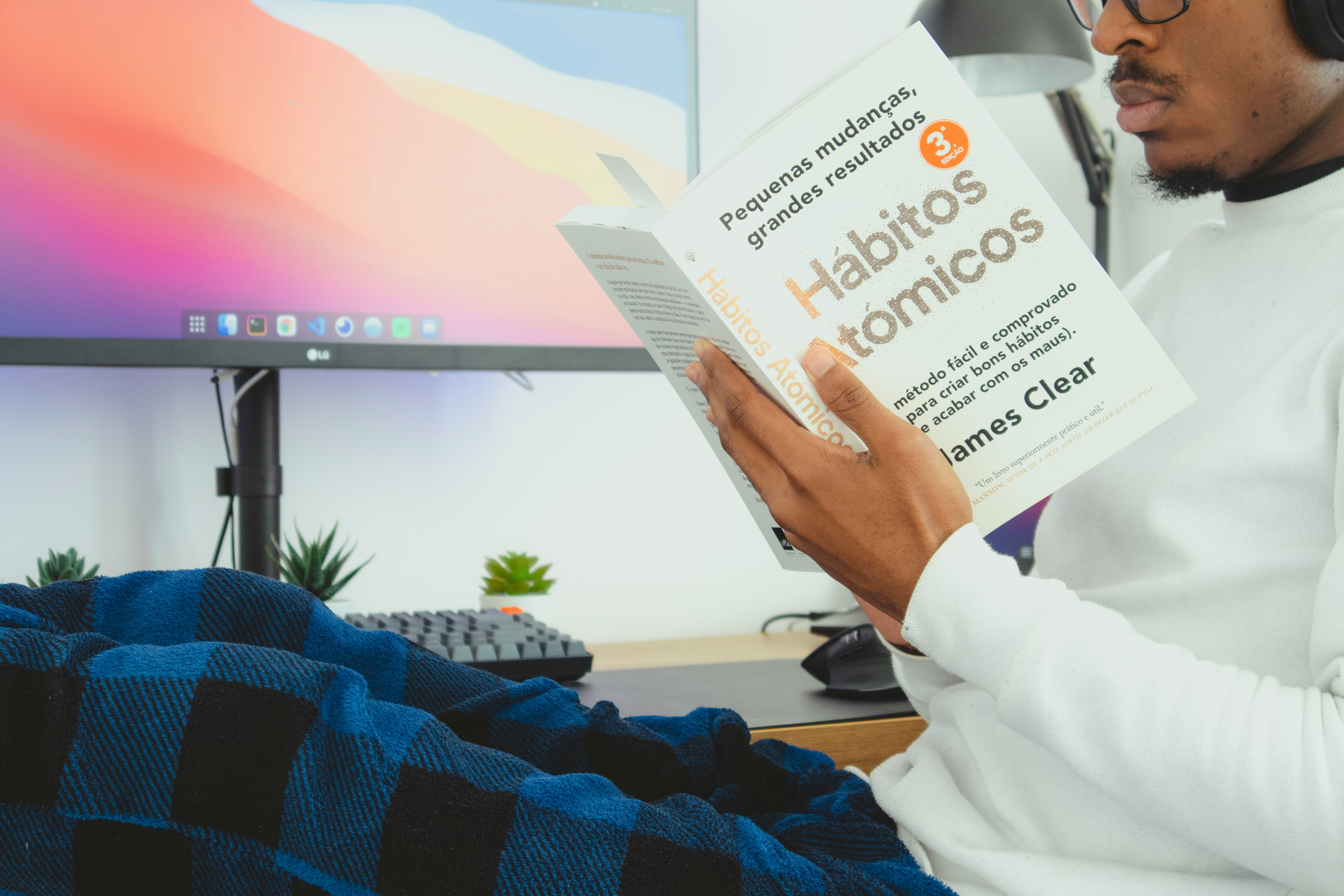 Banner image showing a man reading a spanish translation of James Clear's Atomic Habits